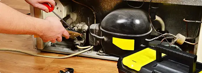 Refrigerator repair technician fixing the compressor and wiring in Chugiak, AK