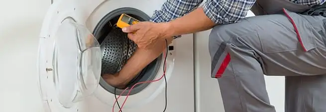 Dryer repair technician inspecting and repairing a clothes dryer in Anchorage, AK