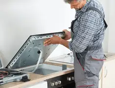 Appliance repair technician installing a built-in cooktop in Anchorage, AK