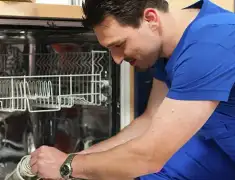 Dishwasher repair technician inspecting and servicing an open dishwasher in Anchorage, AK