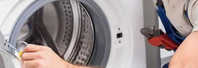 Appliance technician repairing a clothes dryer drum and internal parts in Anchorage, AK