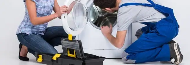Washer repair technician inspecting a front-load washing machine with tools in Anchorage, AK