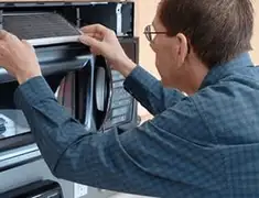 Appliance repair technician replacing a microwave vent filter in Anchorage, AK