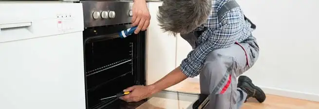 Oven repair technician inspecting and servicing an electric oven in Anchorage, AK