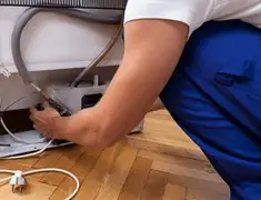 Appliance repair technician fixing refrigerator water line and connections in Anchorage, AK