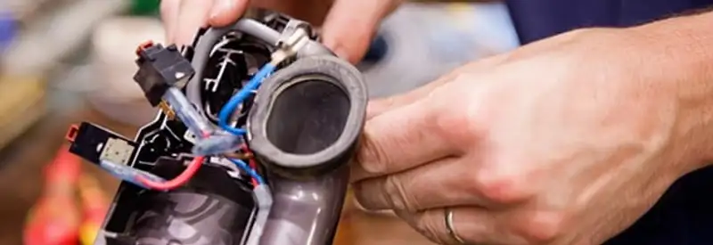 Vacuum repair technician reconnecting wiring and components in Anchorage, AK