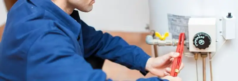Water heater repair technician adjusting the temperature control and gas valve in Anchorage, AK